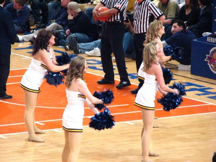 three girls standing on a court holding cheerleaders