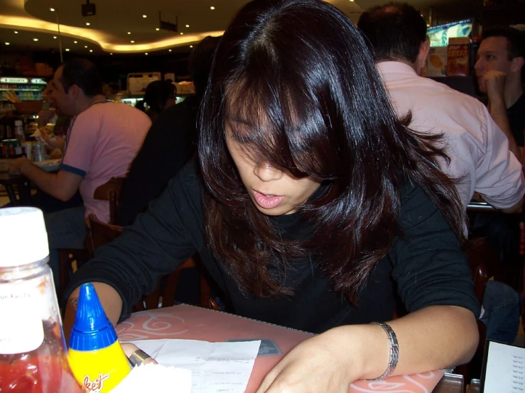 a lady is seated at a table writing soing