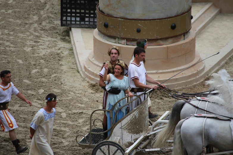 people walking with two small horses behind a carriage