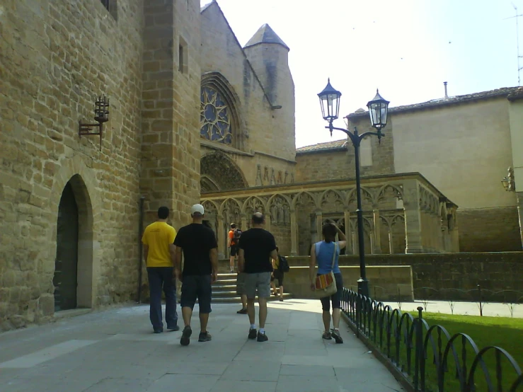 four skateboarders walk up the side of a brick and stone building