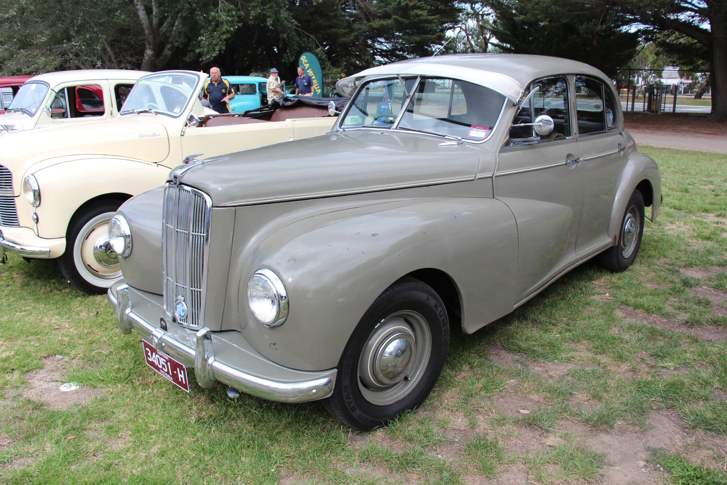 three older classic cars are parked in a field