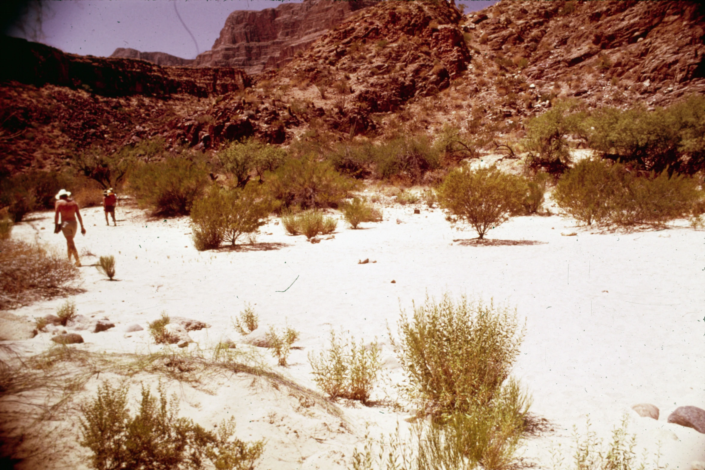 a couple walking through the sand in the mountains