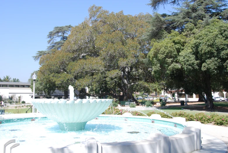 the circular fountain is outside by some trees