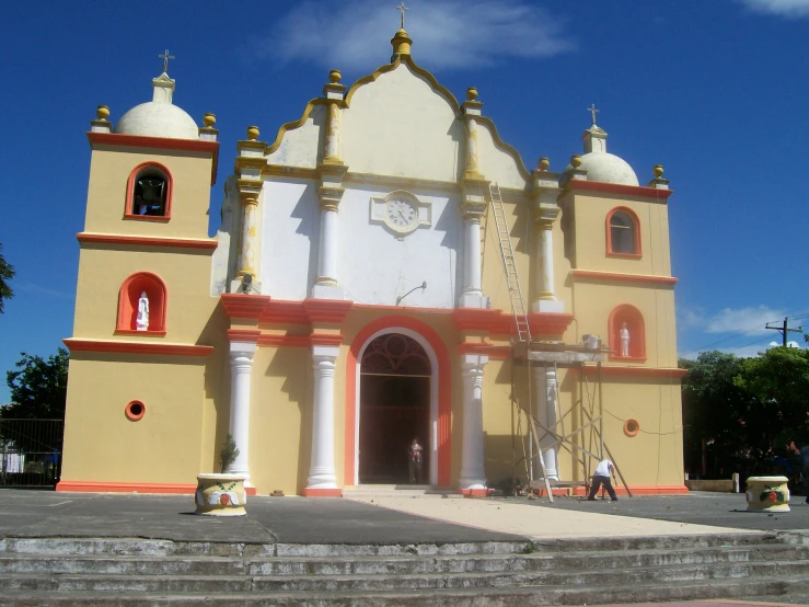 an old yellow and red building with two large domes