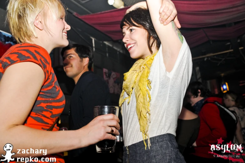 two young ladies with glasses talking while holding their arms up