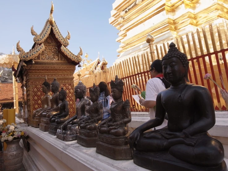 a statue is sitting in front of a row of buddha statues