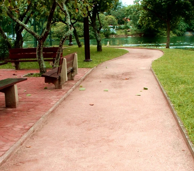 two benches are facing away from the grass on a pathway