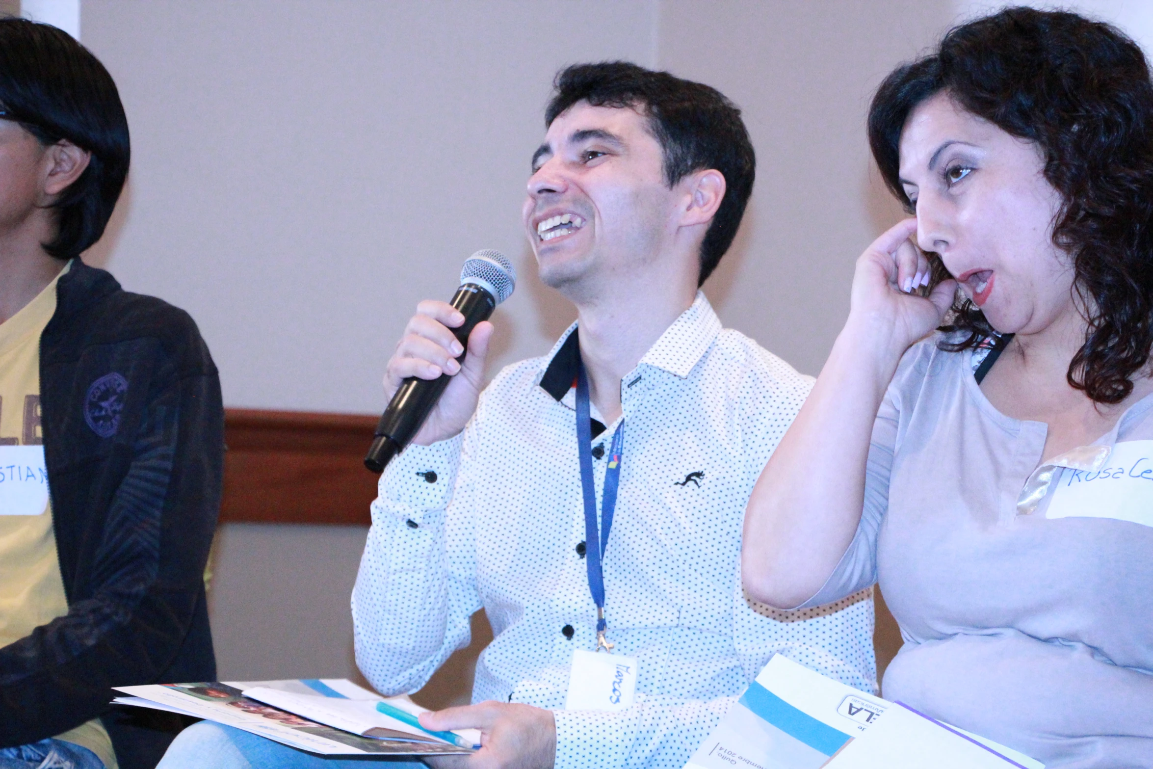 a woman and man are sitting in a group talking on a microphone