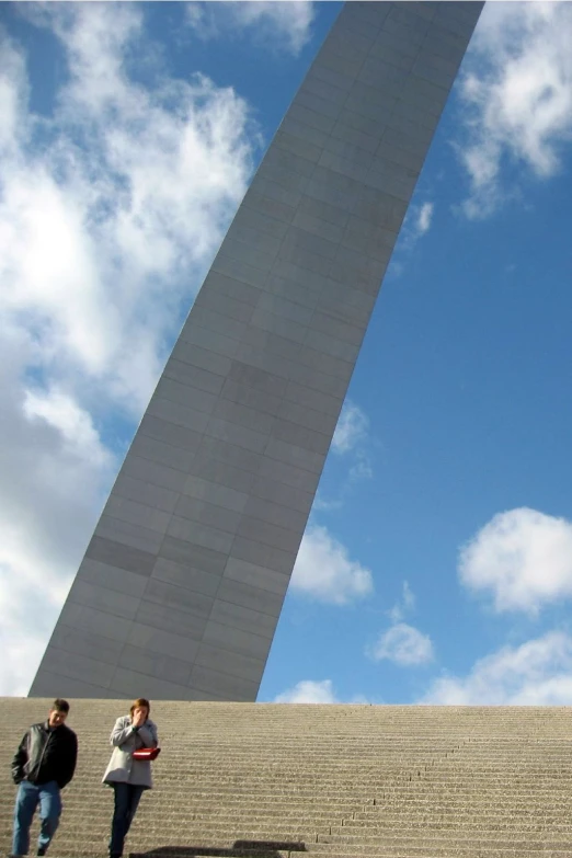 people walking up the steps of a stairway in front of a monument