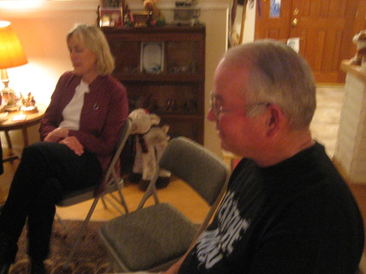 man sitting in a chair with a dog and a woman standing next to him