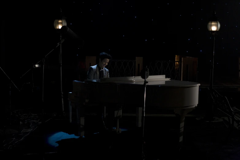 a man playing on an old white piano with a microphone