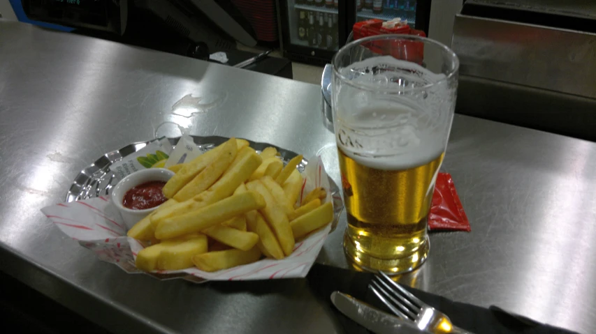 a tray with french fries, ketchup and a mug of beer