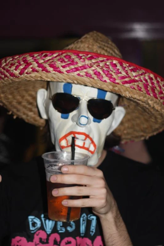 a person with a skull painted mask drinking