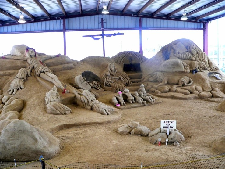 sand sculptures that look like humans and sheep are on display