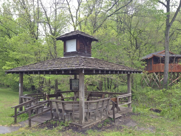 a wooden gazebo on a park near a forest