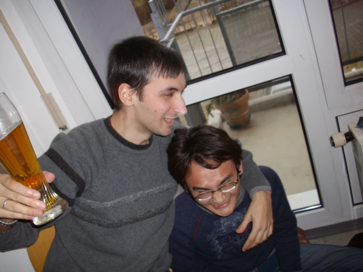 two men are smiling next to each other with beers