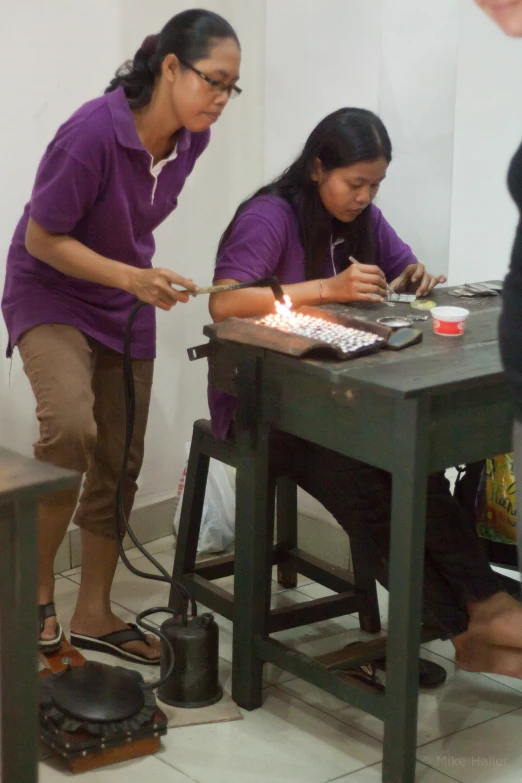 three people sitting at a table working on designs