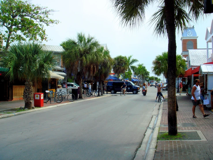 the street is lined with parked cars, motorcycles, and people