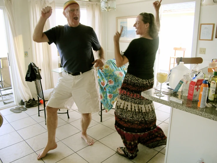 the man and woman are dancing around in their kitchen