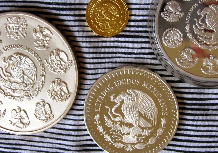 two canadian coins, one gold and one silver, sitting on a striped cloth