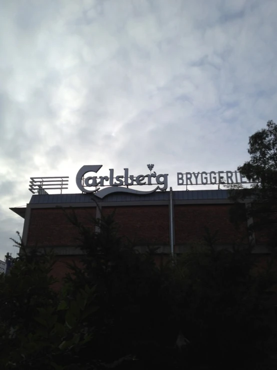 a building under cloudy skies with a sign on top