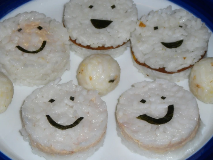 a plate with some rice balls topped in different smiley faces