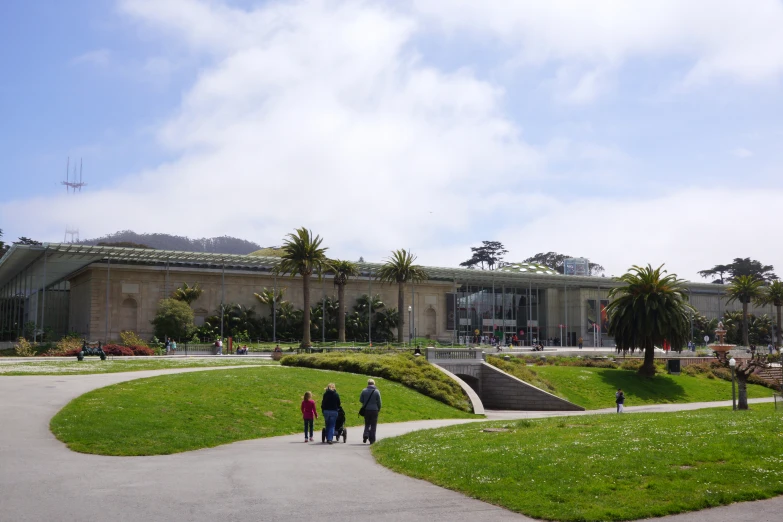 three people walking through a park and a building