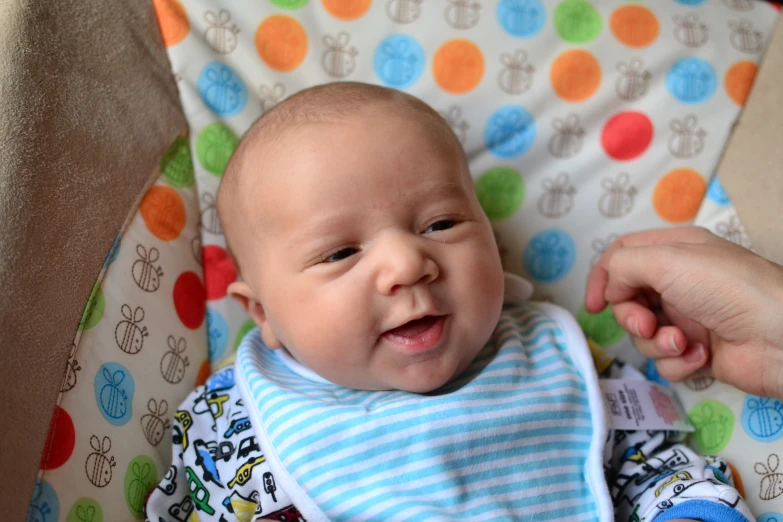 a baby with a blue and white  shirt and bib in a stroller