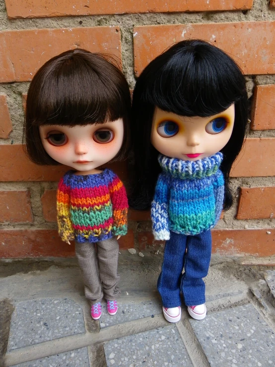 two doll in front of brick wall and stone pavement