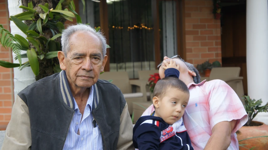 an old man with his hand on the head of a small boy