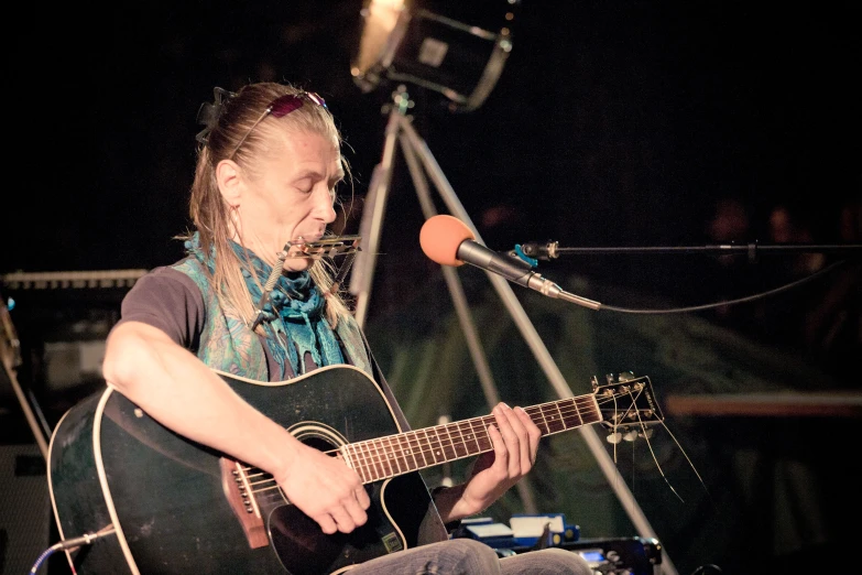 woman playing guitar and singing into microphone