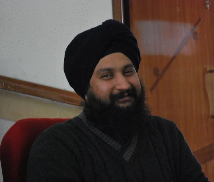 a bearded man in a black hat sitting at a table