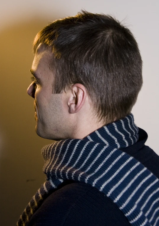 a man is standing against a wall wearing a black and white  scarf