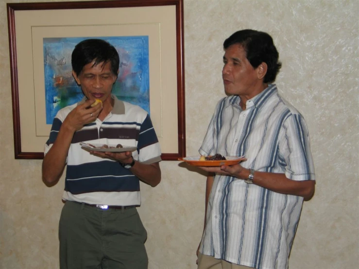 a couple of men standing together and eating food