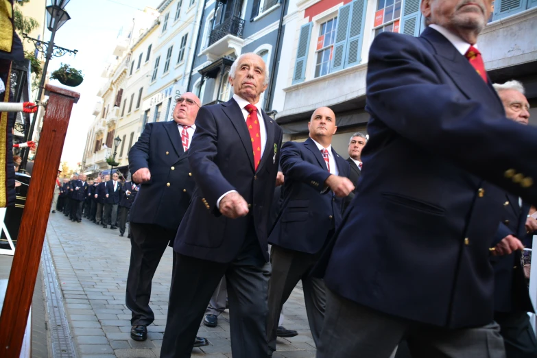 the men wearing red ties are marching down the street