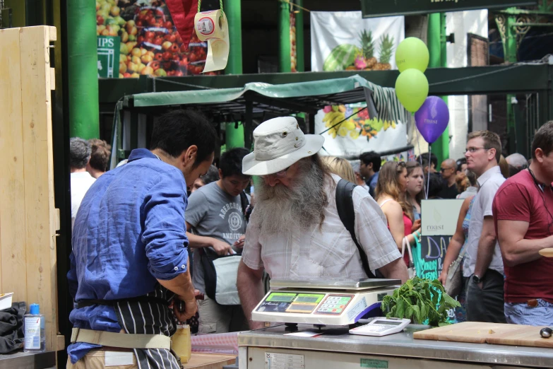 people are gathered in an open market looking at items