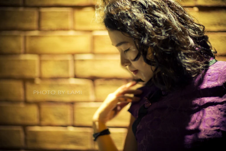 a beautiful woman wearing a purple dress near a brick wall