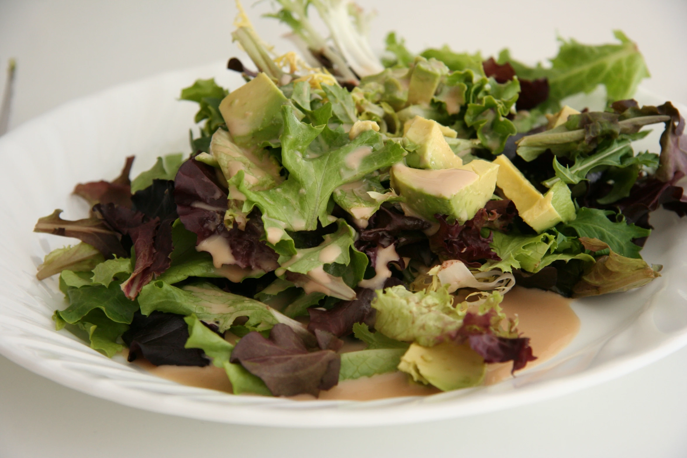 a white plate filled with lettuce, apple and cheese salad