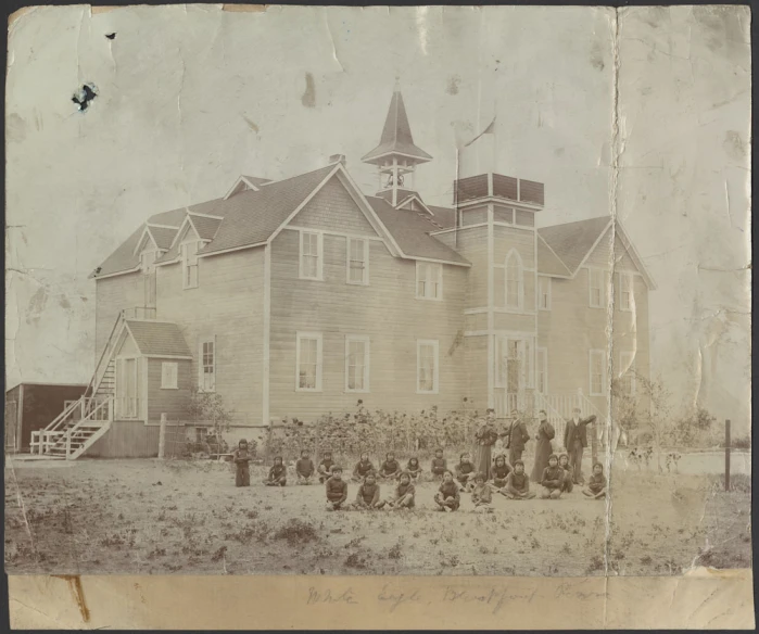 an old po shows an old wooden house with a group of men standing outside