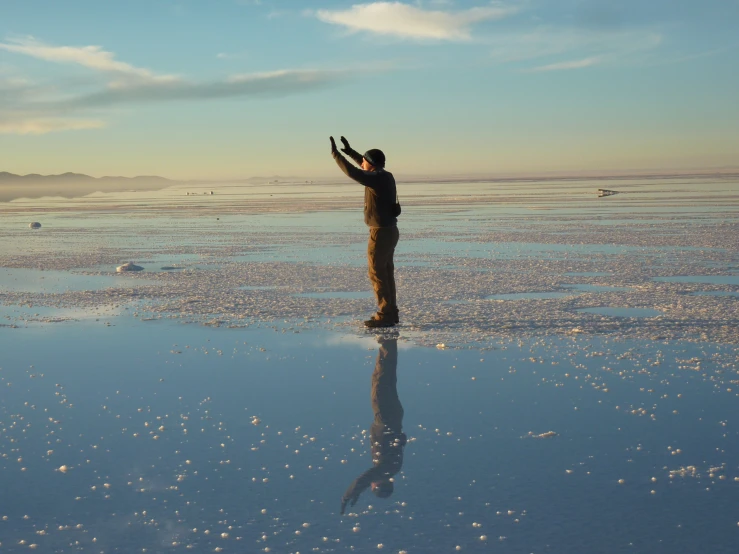 a man on a large flat body of water pointing out his hand