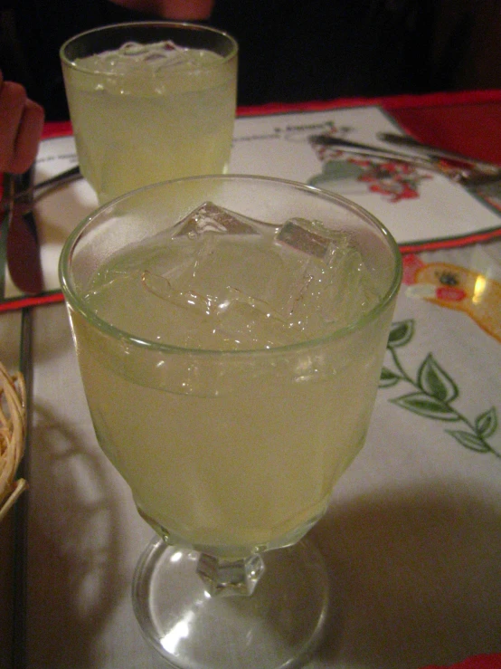 two glasses filled with ice sitting on top of a table