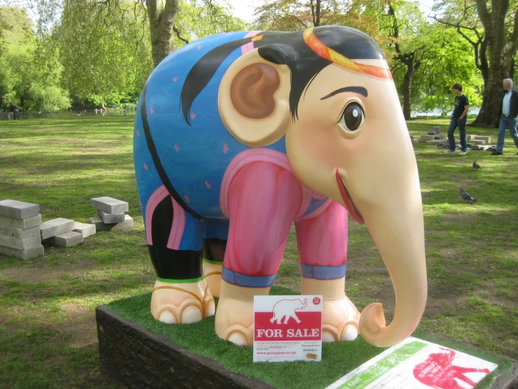 a big fake elephant with some kind of sale sign