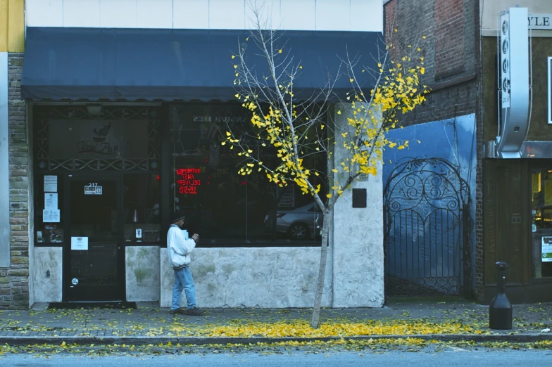 a person stands at the atm on a corner of a street