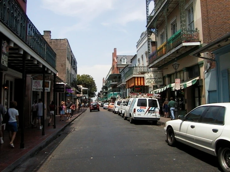 people walk along a street lined with stores