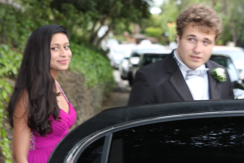 the man and woman are dressed up nicely by their limo