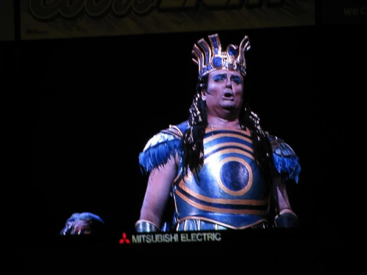 a person dressed as a roman centurine stands in front of a screen that displays the symbol of a new world order