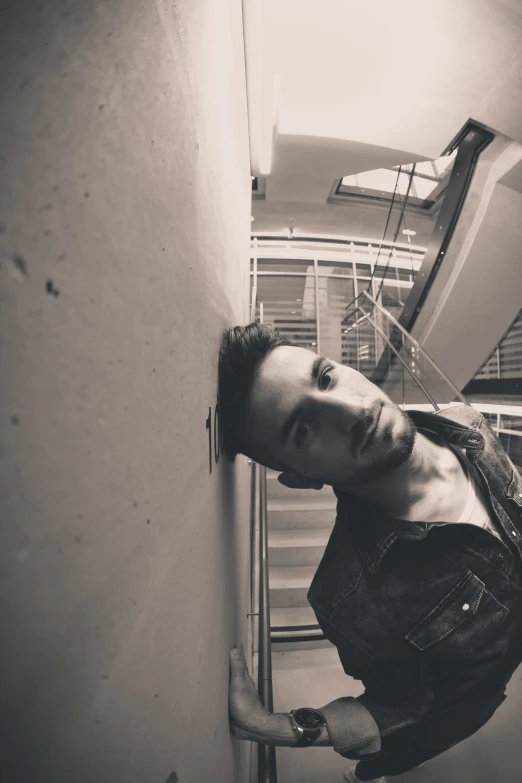 a man standing in a stairwell leaning against a wall