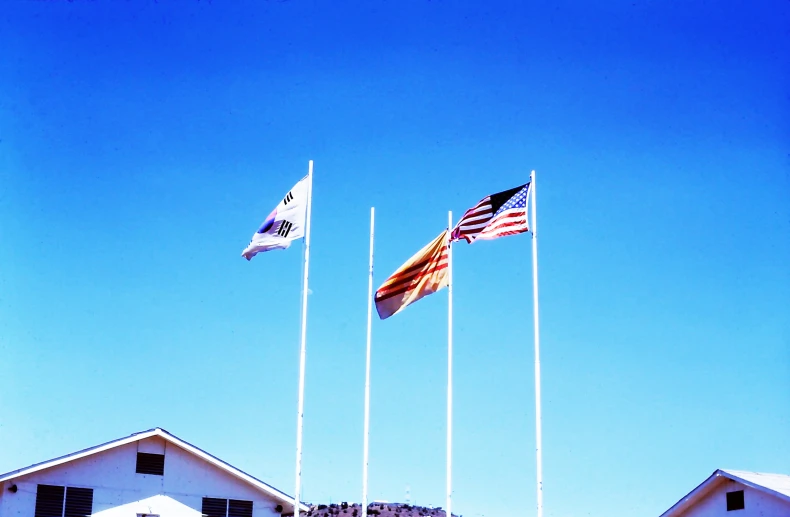 four flags flying from a pole with houses in the background