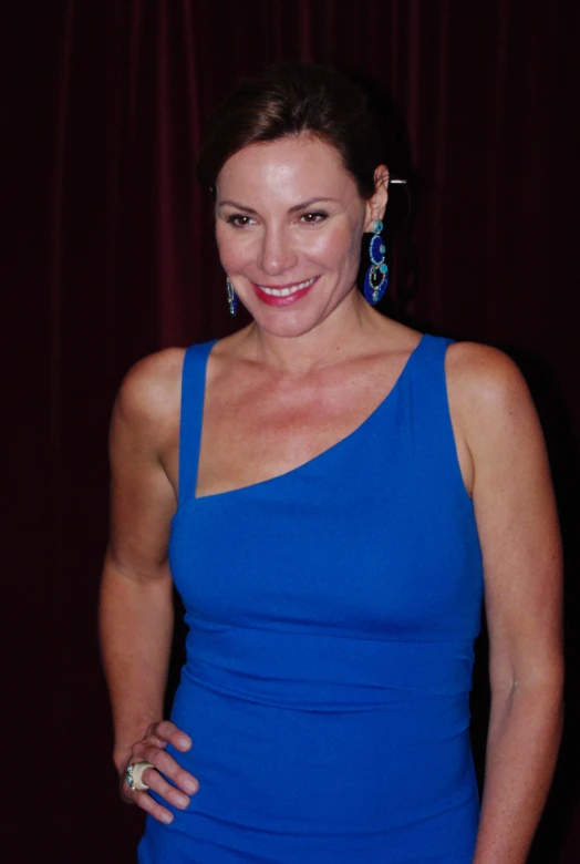 a woman in a blue dress smiles for the camera