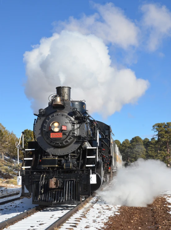 a steam locomotive making it's way through a snowy field